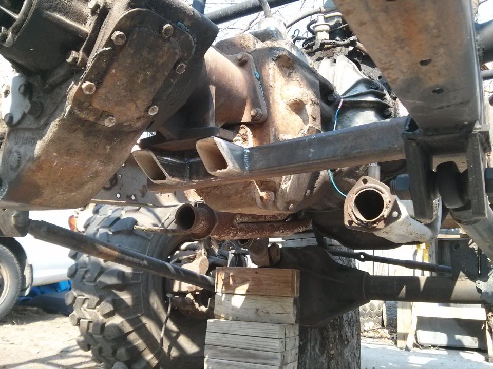 Close-up of vehicle drivetrain and suspension parts, including differential and exhaust pipe