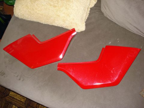2008 Ford Crown Victoria - Two red plastic trim pieces are shown on a couch.