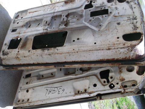 1971 Ford Ranchero - These weathered car doors show signs of rust and wear, with handwritten markings on their surfaces.