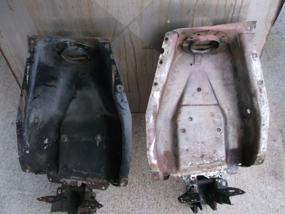 Two old car fuel tanks, one black and one rusty, side by side