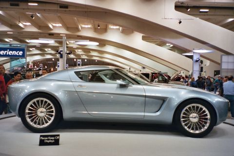 1992 Mercury Grand Marquis - A futuristic silver concept car is displayed at an auto show, with onlookers in the background.