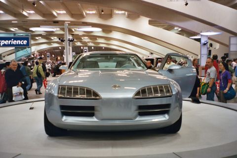 1992 Mercury Grand Marquis - A futuristic silver concept car with its gull-wing doors open is displayed at an auto show.