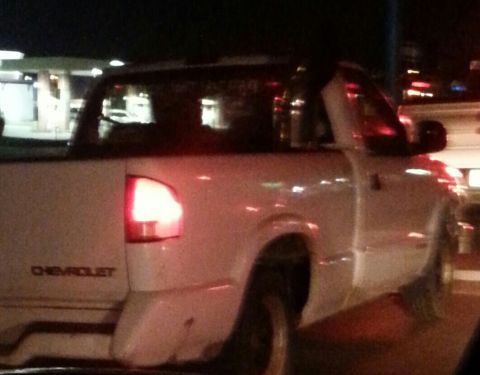 1995 Ford Bronco - A white Chevrolet pickup truck is seen from the rear quarter at night.