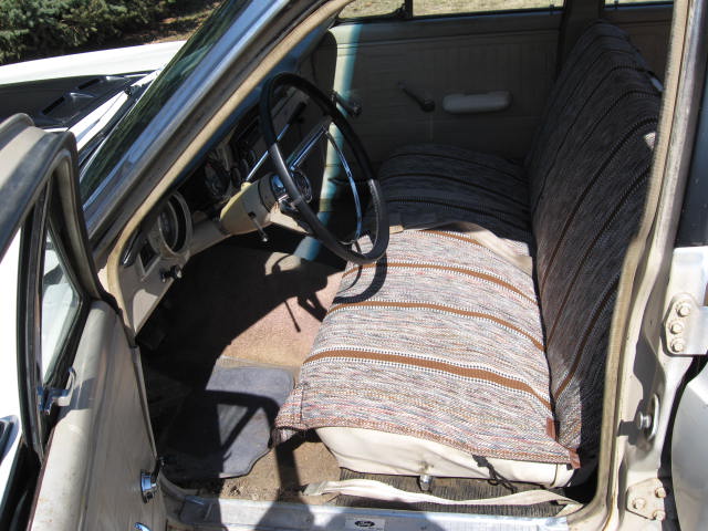 1966 Ford Falcon interior showing front bench seat with striped cover, dashboard, and steering wheel