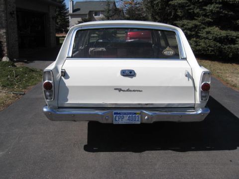 1966 Ford Falcon - The rear of a white 1966 Ford Falcon station wagon is shown, its chrome bumper and a Michigan license plate.