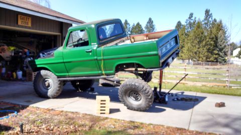 1967 Ford F-250 - A green pickup truck is undergoing maintenance, with its front end raised and hood open.