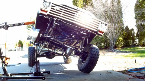 1967 Ford F-250 - A 1967 Ford F-250's front end is lifted, revealing its heavily modified chassis and suspension system.