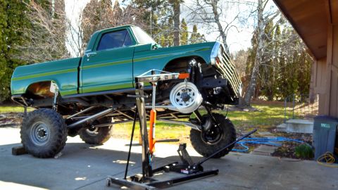 1967 Ford F-250 - Green pickup truck undergoing front-end work, showing its lifted suspension and custom grille.
