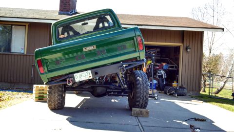 1967 Ford F-250 - Rear view of a modified green pickup truck with custom suspension and large tires.
