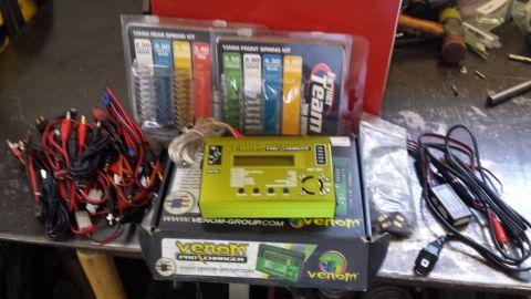 1996 Ford Bronco - A collection of RC car accessories, including a charger and various wiring, are laid out on a workbench.