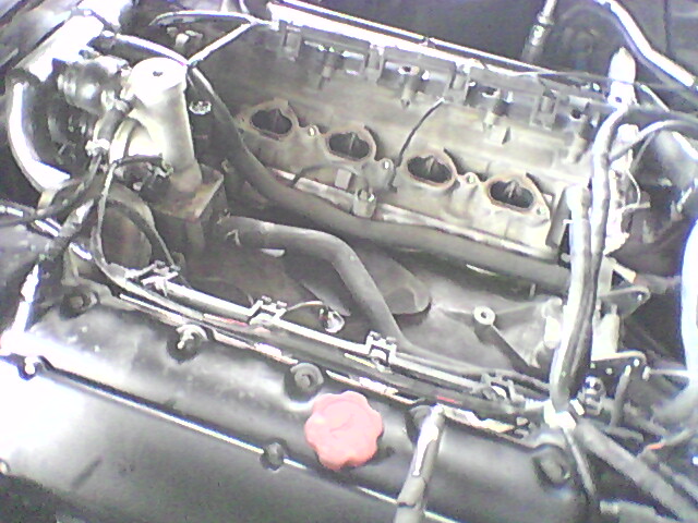 Engine bay with hoses and wiring visible, a red cap on the left