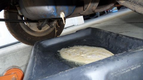 1972 Ford Ranchero - Oil draining from a vehicle's undercarriage into a collection pan, with the Supermotors.net logo visible in the lower right corner.