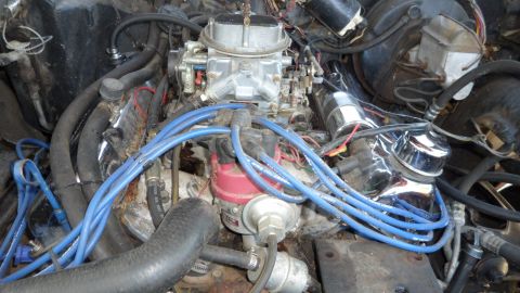 1972 Ford Ranchero - Close-up view of a vehicle's engine bay, a carburetor and blue spark plug wires.