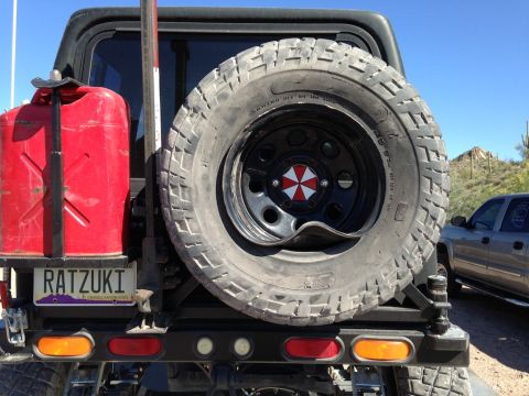 1987 Suzuki Samurai - This off-road vehicle is equipped with a spare tire, a red jerrycan, and a custom license plate.