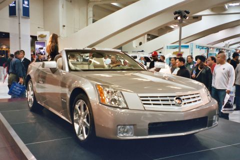 1992 Mercury Grand Marquis - A silver convertible Cadillac is showcased at an auto show, drawing attention from onlookers.