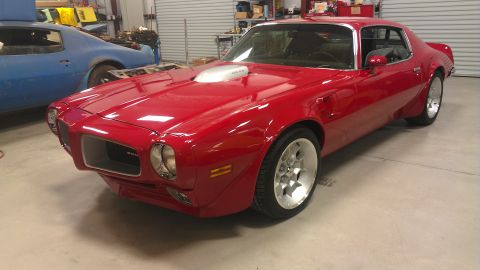 1972 Pontiac Trans Am - A red Pontiac Firebird is parked in a garage next to a blue car.