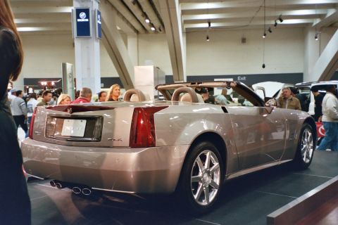 1992 Mercury Grand Marquis - A silver convertible is displayed indoors at an auto show with people in the background.