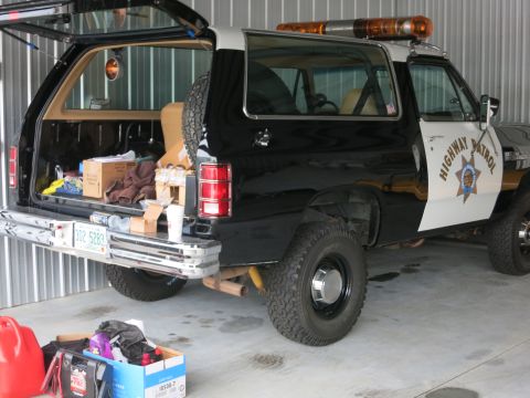 1991 Ford LTD Crown Victoria - Highway Patrol Dodge Ramcharger SUV parked inside a garage, rear view with tailgate open.