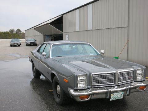 1991 Ford LTD Crown Victoria - Gray 1977 Dodge Monaco with a distinctive grille, parked outside a large building.