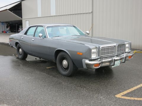 1991 Ford LTD Crown Victoria - This Dodge Monaco is parked on a wet asphalt lot in front of a large industrial building.