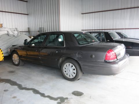 1991 Ford LTD Crown Victoria - A dark gray Ford Crown Victoria is parked inside a garage, with another vehicle visible behind it.