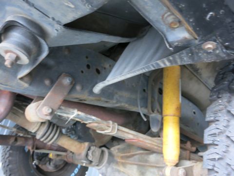 1991 Ford LTD Crown Victoria - The undercarriage of a truck reveals its suspension system, including a leaf spring and a yellow shock absorber.
