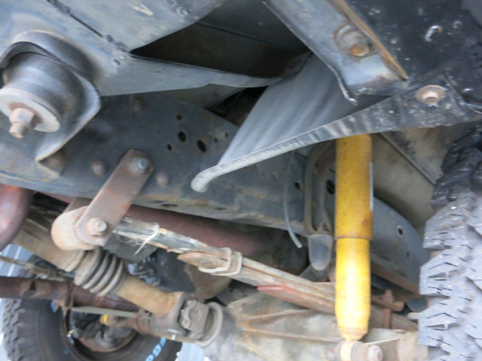 Underside view of a truck's frame, showing suspension components like a leaf spring and yellow shock absorber