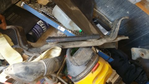 1986 Ford Bronco - A metal bracket with a rubber mount is shown among various automotive parts and tools.