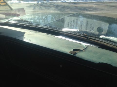 1979 Ford Bronco - Interior view of a vehicle's dashboard and windshield, showing wear and a sticker on the glass.