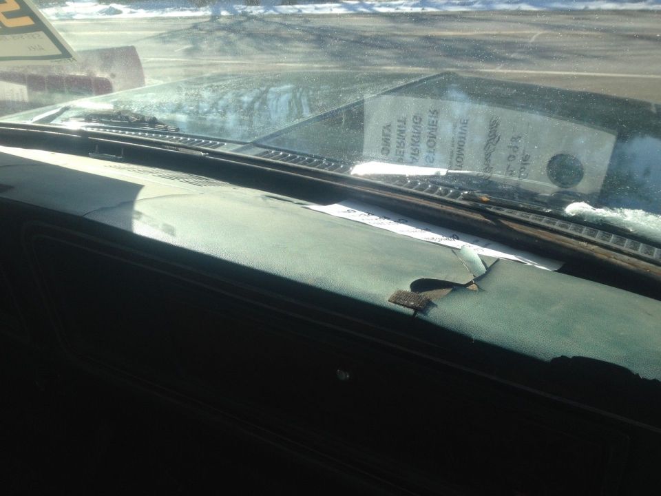 Cracked dashboard and windshield interior with a sticker on the glass