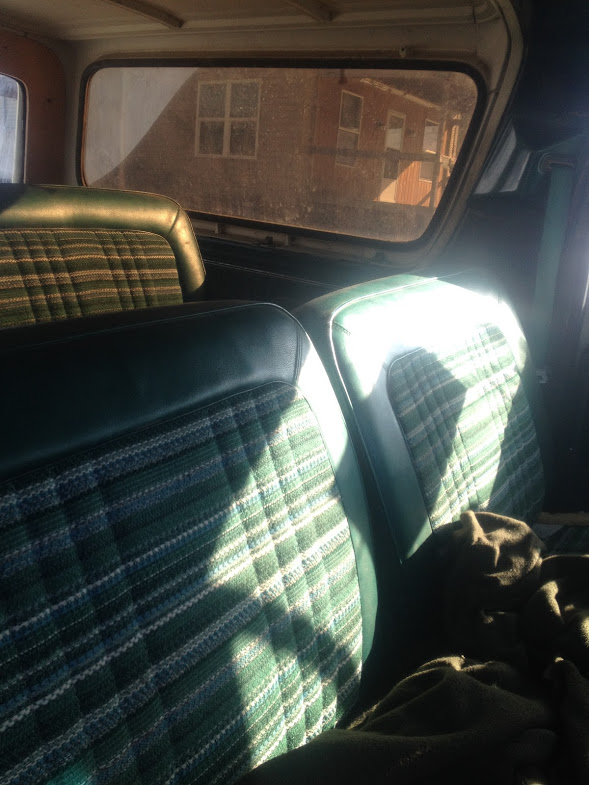 Green plaid and dark green vinyl interior seats with sunlight streaming through the rear window