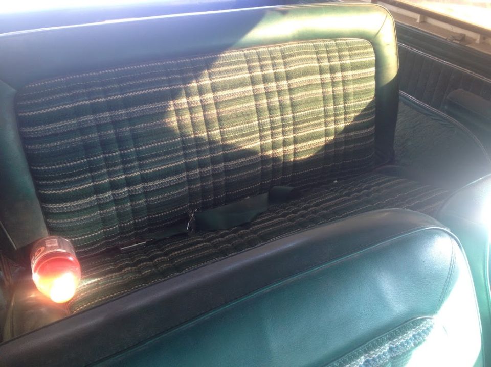 Back seat with green plaid upholstery and a seatbelt
