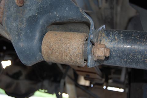 1994 Ford Bronco - Close-up of a rusty suspension bushing and bolt on a vehicle's undercarriage.