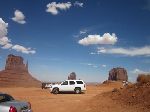 1991 Ford LTD Crown Victoria - A white SUV and a silver sedan are parked in the desert landscape of Monument Valley.