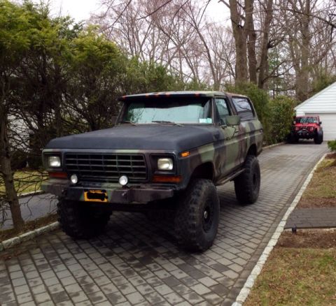 1979 Ford Bronco - Camouflaged Ford Bronco with lifted suspension and large tires parked on a driveway.