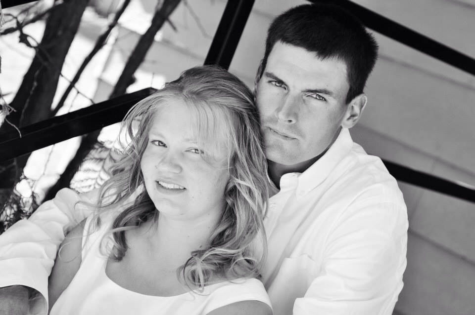 Couple posing for a photo, with a watermark at the bottom right