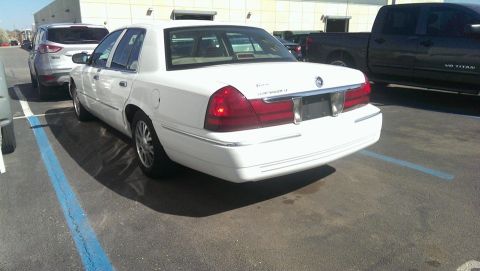 2000 Mercury Grand Marquis - A white sedan is parked in a lot next to an SUV and a pickup truck.