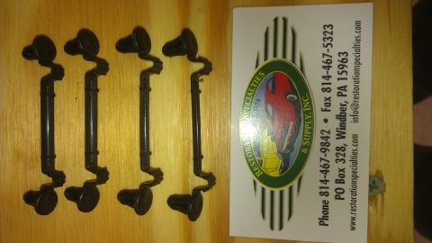 1973 Chevrolet Camaro - Four black metal brackets are laid out on a wooden surface next to a business card.
