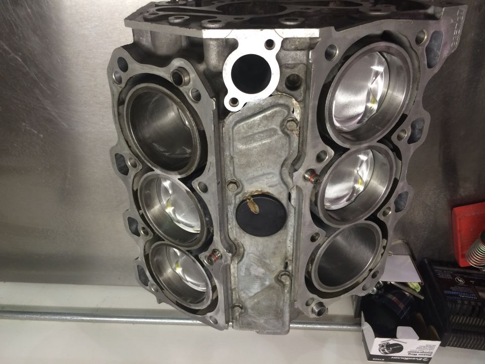 Engine block with six cylinders visible, some with pistons inside