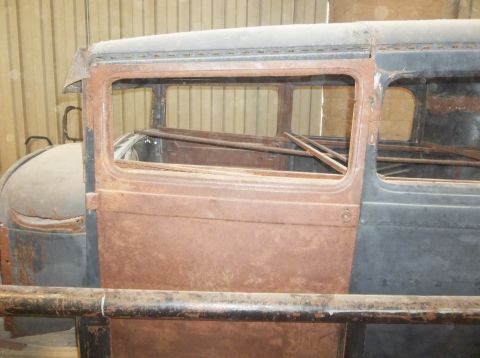1929 Ford Sedan - Side view of a heavily rusted 1929 Ford Sedan door and window frame, interior bracing visible.