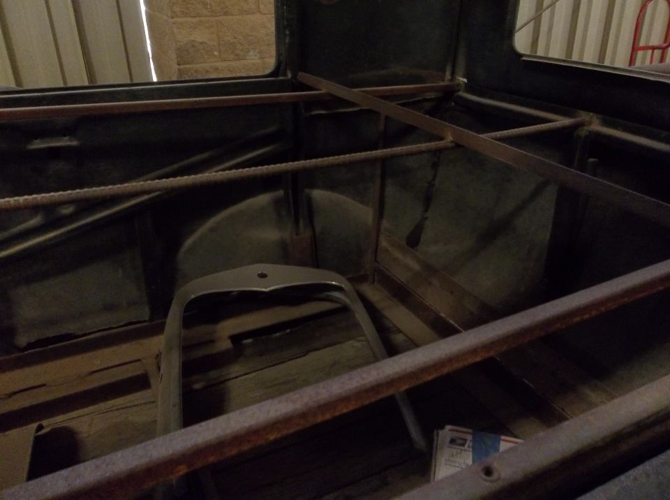 Inside of a car, showing wooden floor and metal framing. A grille is visible