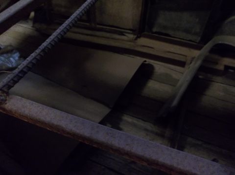 1929 Ford Sedan - The interior of a wooden structure, possibly a shed or barn, with visible metal supports.