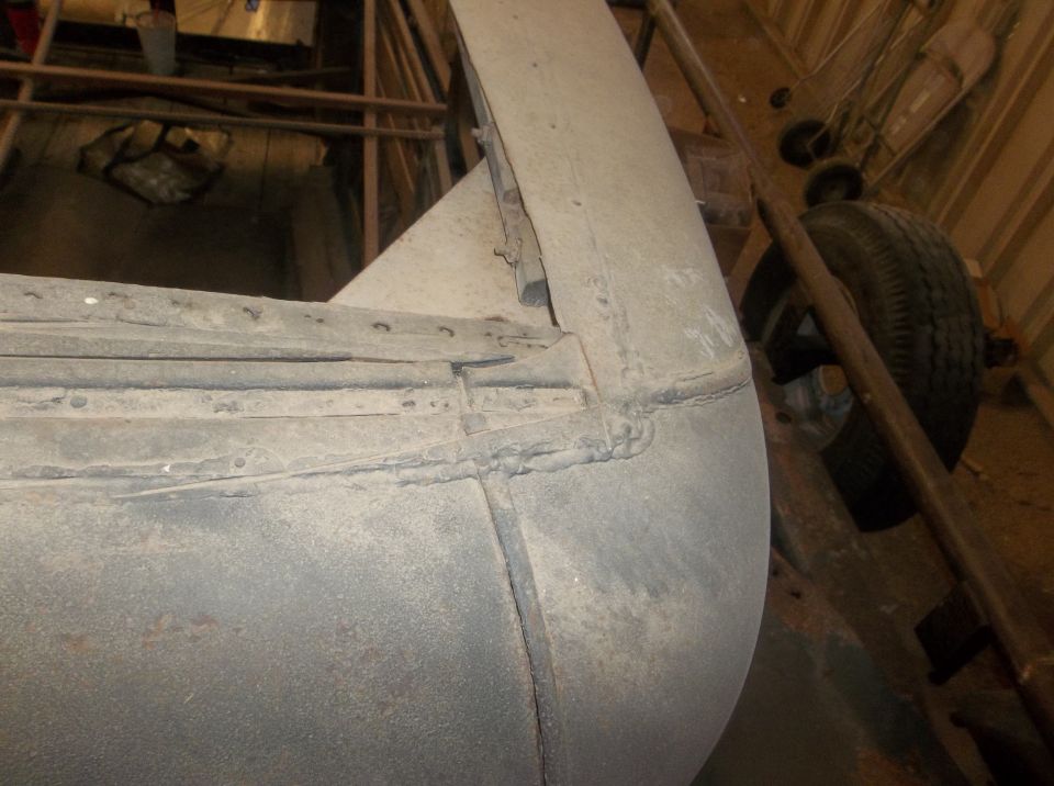 Close-up of a car's rear fender and wheel well, showing metalwork and a tire