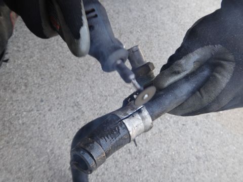 1993 Ford Taurus - A gloved hand uses a rotary tool with a cutting wheel to cut a rubber hose.