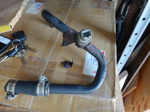 1993 Ford Taurus - A close-up of a corroded metal pipe with a sensor and a rubber hose attached with clamps.