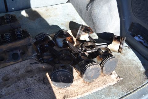 1981 Ford F-250 - Engine cylinder head and several pistons with connecting rods are laid out on a towel inside a vehicle.