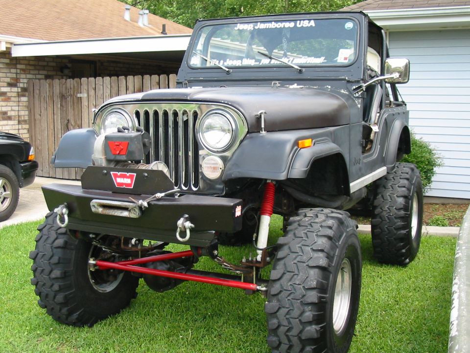 Black lifted Jeep CJ with Warn winch and red shocks parked on grass
