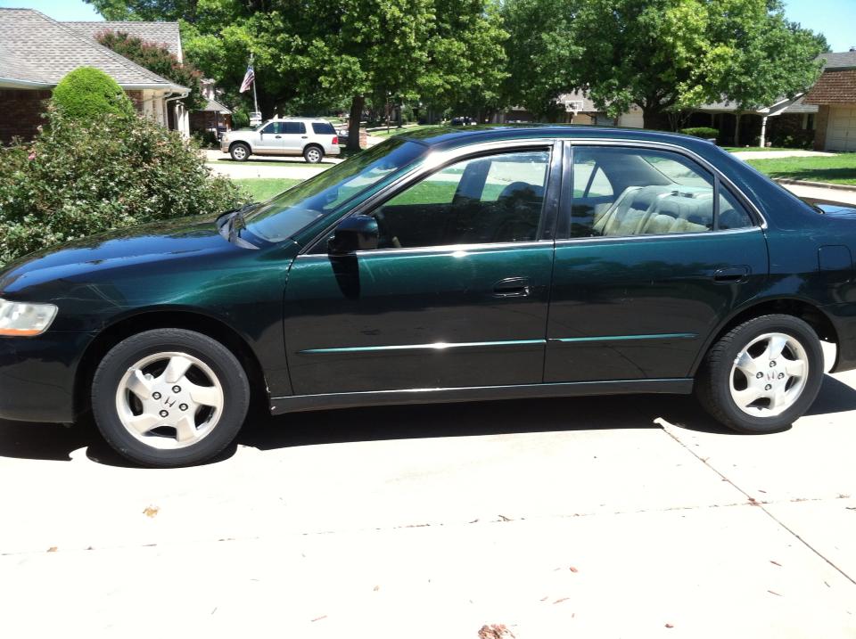 Side view of a dark green sedan parked on a driveway