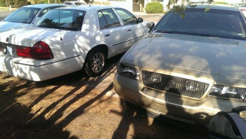 2000 Mercury Grand Marquis - Front view of a gold 2000 Mercury Grand Marquis, parked next to a white sedan.