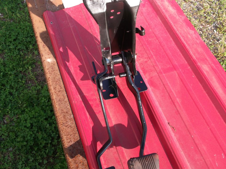 Brake and clutch pedals assembly on red surface